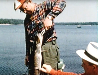 fisherman holding a fish while another man touches it